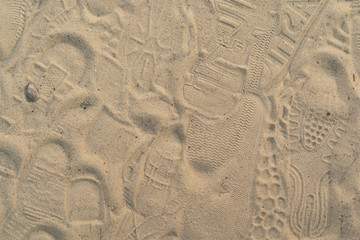 Sand on the beach with footprints and shoes. Many footprints with shoes and without shoes.