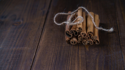 Cinnamon sticks tied with jute rope on old wooden background in rustic style. Winter Christmass holiday concept. Close up.
