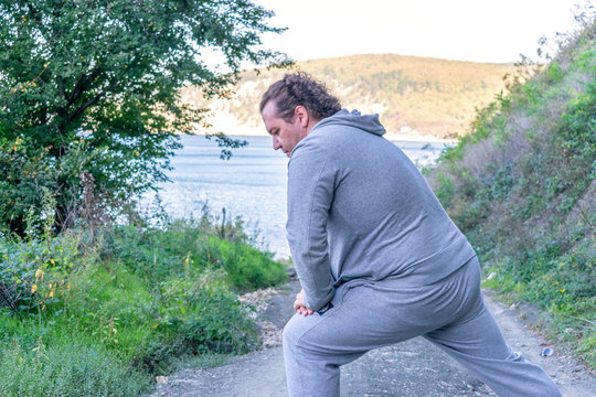 Fat man doing warm-up in nature. Fresh air, sport and a healthy lifestyle