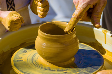 hands of the skilled master Potter and children's hands, training of the kid to production of pottery on a Potter's wheel