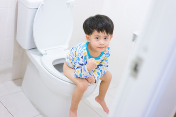 Little boy poo and pee in white toilet.