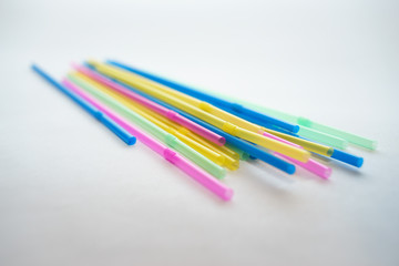 Multiple plastic straws laying on a white background