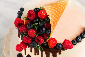 Festive cake with melting chocolate and assorted fruits in a waffle horn on neutral background. Copy space. Vertical. Celebration concept. Close-up. Celective focus.