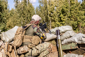 special forces, soldier assault rifle with silencer, optical sight. behind cover waiting in ambush