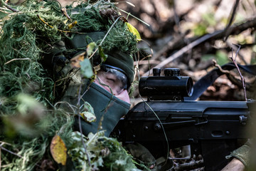 special forces, soldier assault rifle with silencer, optical sight. behind cover waiting in ambush