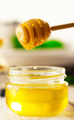 Honey with wooden honey dipper on wooden table