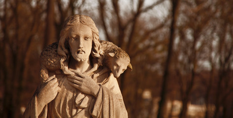 Ancient statue of Jesus Christ is the Good Shepherd with the lost sheep on his shoulders. (Biblical...