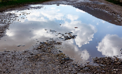 Reflection of sky sun  & clouds in Puddles A silent and sandy road on a very bad condition This is...