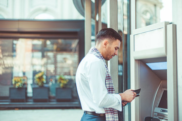 Good looking businessman standing next to the ATM