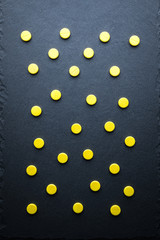 Round Yellow Drugs, Pills, Vitamins Scattered On A Gray Slate Background. Medical Series. Top View.
