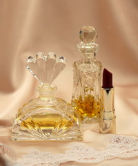 Antique perfume bottles and lipstick on the background of silk and lace