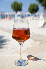 One glass of cold rose wine served on the beach with beautiful sea view. Relax concept. Bright sunny day with blue sky.