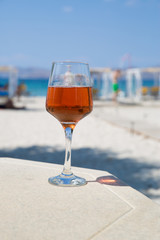 One glass of cold rose wine served on the beach with beautiful sea view. Relax concept. Bright sunny day with blue sky.