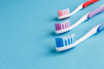 concept of dental health. Three multicolored toothbrush and toothpaste on a blue background. Design, health care, healthy hygiene
