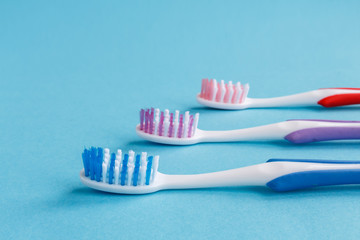concept of dental health. Three multicolored toothbrush and toothpaste on a blue background. Design, health care, healthy hygiene