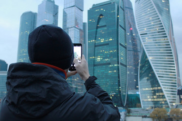 A man photographs the skyscrapers on the phone