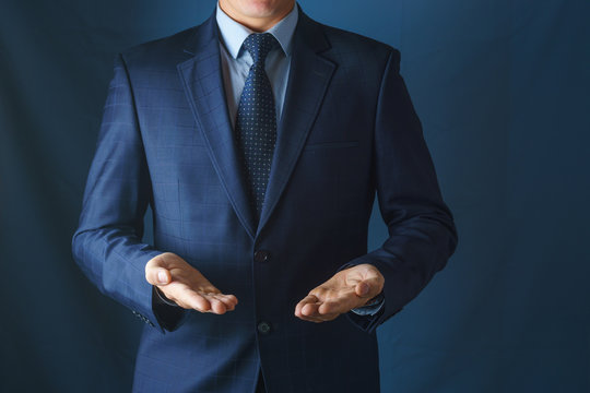 Man in suit holds hands with palms up.