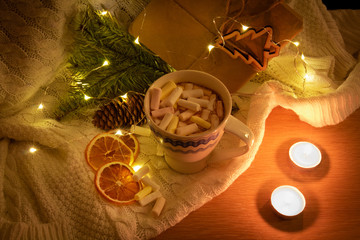  a mug of hot chocolate with marshmallows near candles and fires