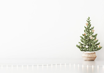 Interior white wall mock up with decorated christmas tree in basket and garland lights on empty background. 3D rendering.