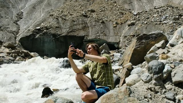 Tourist photographs on phone panoramic landscape - mountain river and glacier