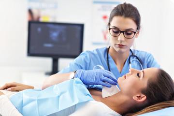 Adult woman having thyroind ultrasound test at female doctor's office - obrazy, fototapety, plakaty