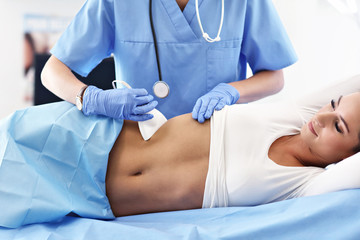 Adult woman having abdomen ultrasound tests at female doctor's office