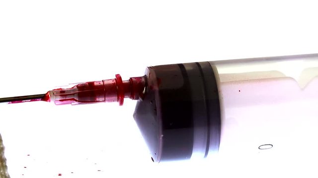 A syringe is filled with a red substance
