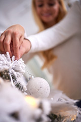 A beautiful young happy couple decorating the christmas tree together.