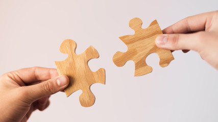Two hands trying to connect couple wooden puzzle piece. Concept of association and connection, business strategy.