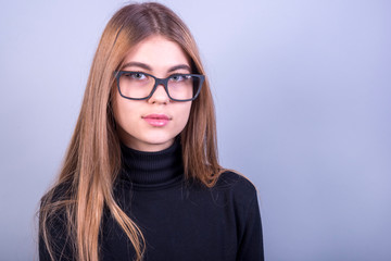 Young beautiful girl with glasses standing in front of grey background