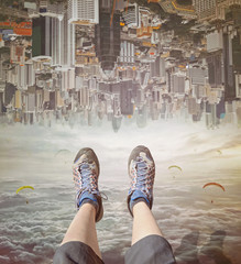 Legs of a woman  in sneakers relaxing in sky.  Invert  city upside down .Future modern business...