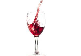 Red wine falls into a glass and creates splash and splashes on a white background.