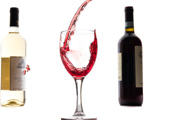 Red wine falls into a glass and creates splash and splashes on a white background.