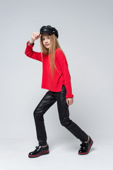 Portrait of beautiful young redhead girl wearing red sweater and black pants posing in studio.