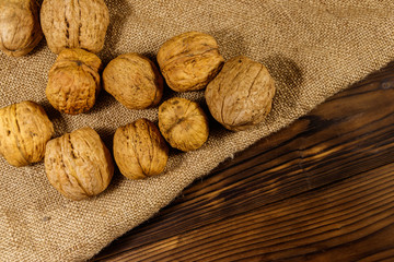 Walnuts on burlap on wooden table. Top view