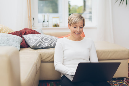 Blond woman smiling as she works on her laptop