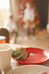 New Year's interior home cooking. Garlands in bokeh. Beautiful red and white plates and cups on a wooden table. Cozy atmosphere. Christmas mood.
