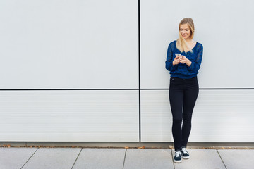 Blond woman using a mobile on an urban sidewalk