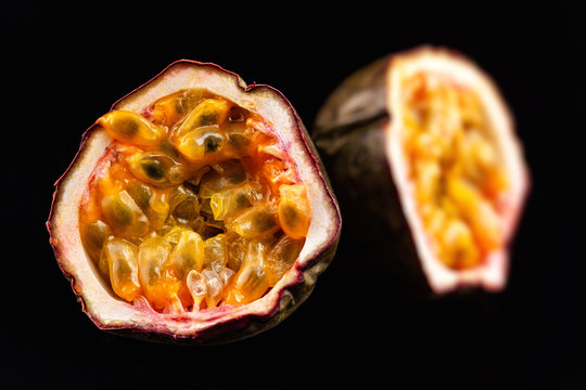 Macro image of two halves of passion fruit isolated at black background.
