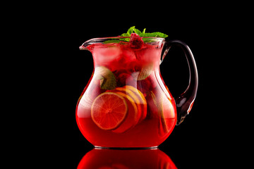 Glass jar of red wine sangria with wild berries and citrus mix isolated at black background.