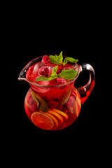 Glass jar of red wine sangria with wild berries and citrus mix isolated at black background.