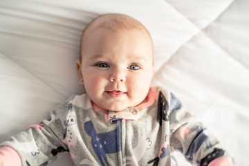 A Cute baby girl on a white bed at home