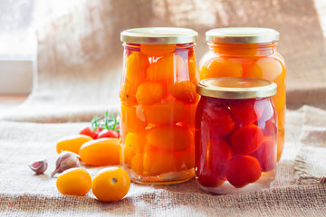 Glass jars with homemade pickled tomatoes, sealed with metal lid