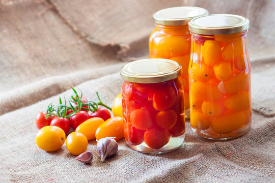 Glass jars with homemade pickled tomatoes, sealed with metal lid