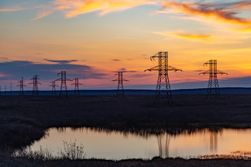 Silhouette of high voltage posts at sunset. Norilsk.