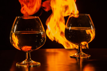 Two glasses with water on the background of red flame with reflections