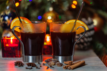 Mulled wine with orange and cinnamon on the blurred background of Christmas decorations. Traditional hot drink at Christmas time