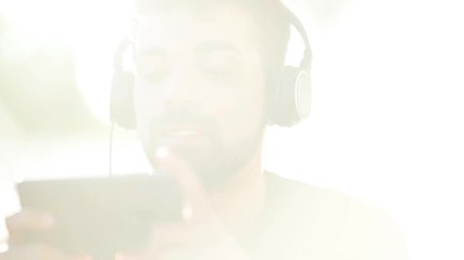 Millenial young man using his smartphone for listening music with headphones
