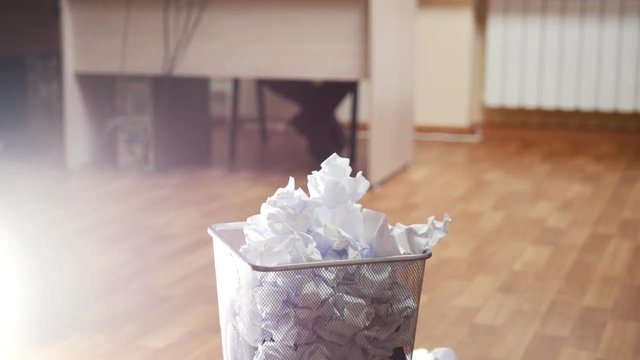 An angry man in office writing something and throws paper in trash