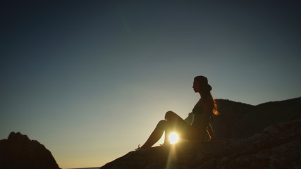 Woman sets on the beach on sunset, outdoor shoot